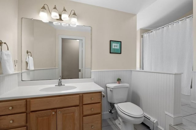 bathroom with baseboard heating, a wainscoted wall, tile patterned floors, vanity, and toilet