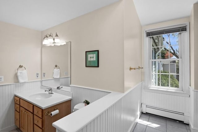 bathroom with a healthy amount of sunlight, wainscoting, vanity, tile patterned floors, and a baseboard radiator