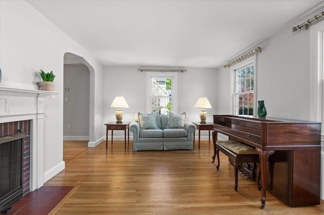 living room with arched walkways, baseboards, wood finished floors, and a fireplace