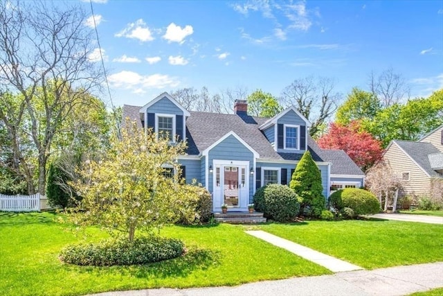cape cod-style house with fence, a chimney, roof with shingles, and a front yard
