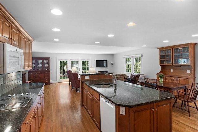kitchen with a sink, light wood-style floors, white appliances, and open floor plan