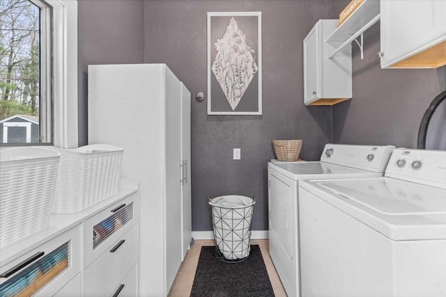 washroom featuring cabinet space, washing machine and clothes dryer, and baseboards
