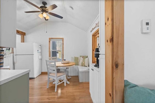 dining space with a ceiling fan, lofted ceiling, and light wood-style floors