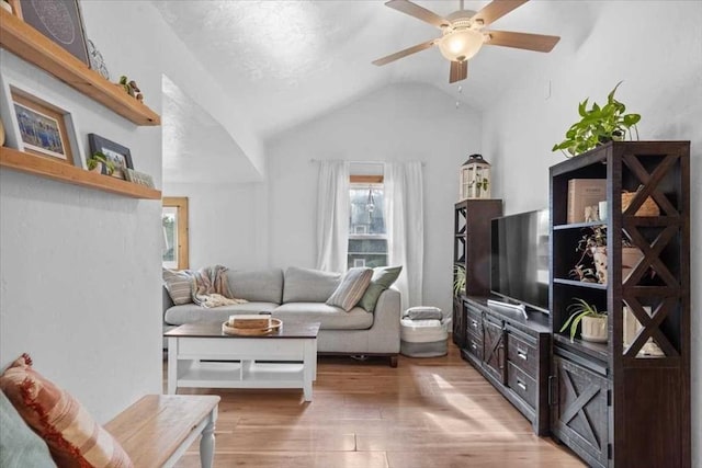 living room featuring a ceiling fan, light wood-style floors, and lofted ceiling