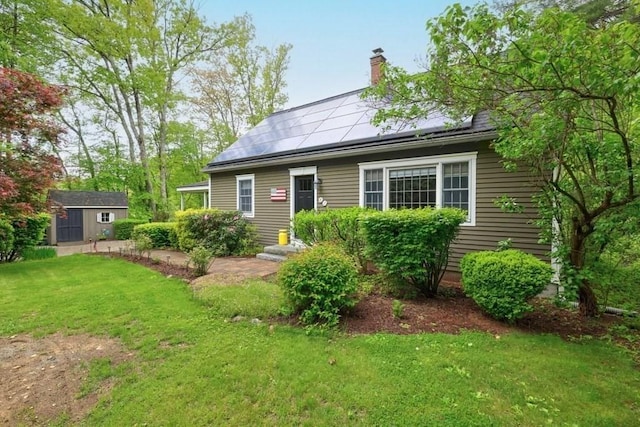 83 Everett Rd, Barre, MA 01005 - view of front of property with a front lawn, a chimney, roof mounted solar panels, and an outdoor structure