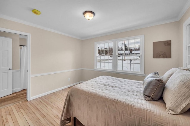 bedroom with baseboards, ornamental molding, and wood finished floors