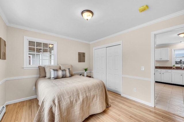 bedroom with baseboards, ornamental molding, a baseboard radiator, and light wood-style floors