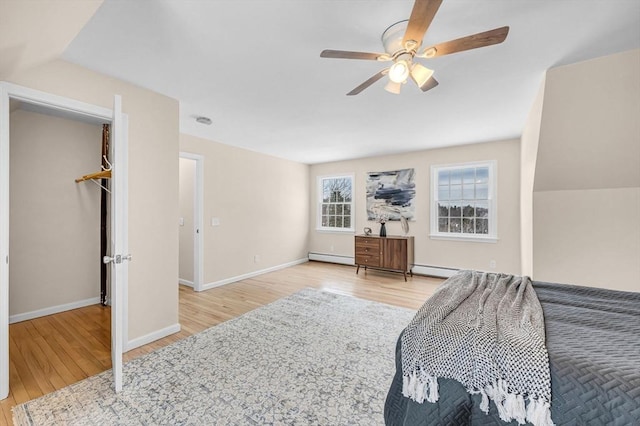 bedroom featuring a ceiling fan, baseboards, wood finished floors, and a baseboard heating unit