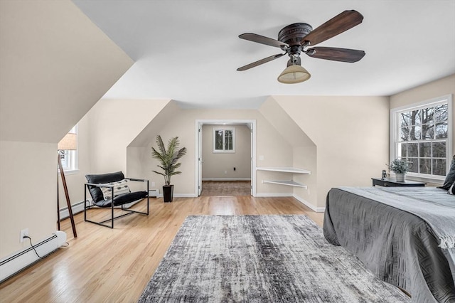 bedroom featuring multiple windows, baseboard heating, a baseboard radiator, and wood finished floors