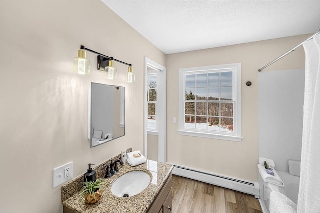 full bath with a baseboard radiator, vanity, a textured ceiling, and wood finished floors