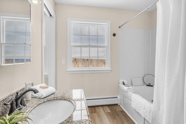 bathroom featuring a baseboard heating unit, wood finished floors, vanity, and shower / bathtub combination with curtain