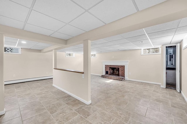 basement featuring a drop ceiling, a fireplace, visible vents, baseboards, and baseboard heating