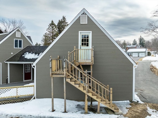 snow covered rear of property with stairway