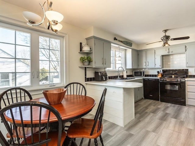 kitchen with gray cabinets, kitchen peninsula, decorative backsplash, and black appliances