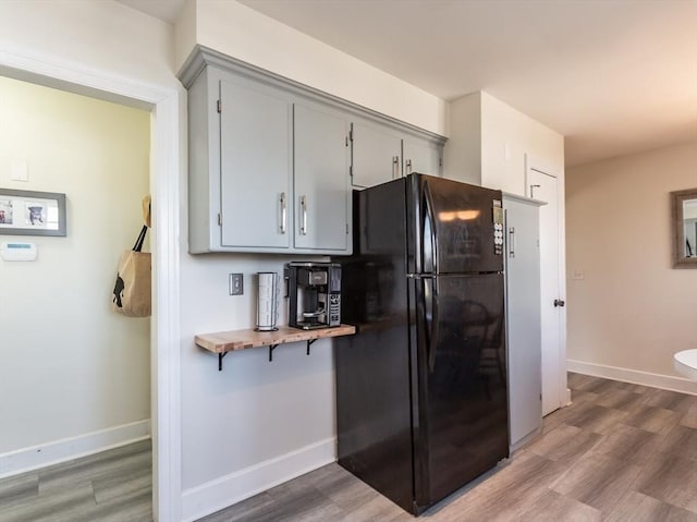 kitchen with black fridge, hardwood / wood-style floors, and gray cabinetry