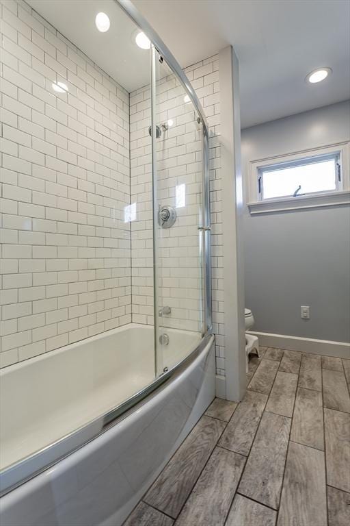 bathroom featuring bath / shower combo with glass door and toilet