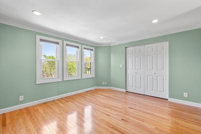 unfurnished bedroom featuring a closet, ornamental molding, wood finished floors, baseboards, and recessed lighting