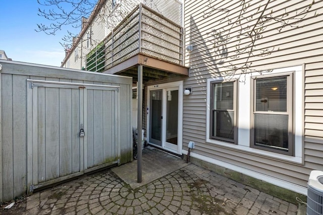 exterior space featuring central air condition unit, a balcony, a shed, and an outbuilding