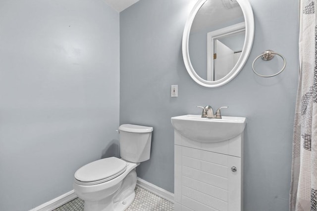 bathroom featuring tile patterned flooring, baseboards, toilet, and vanity