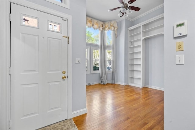 foyer entrance with crown molding, plenty of natural light, a ceiling fan, and wood finished floors