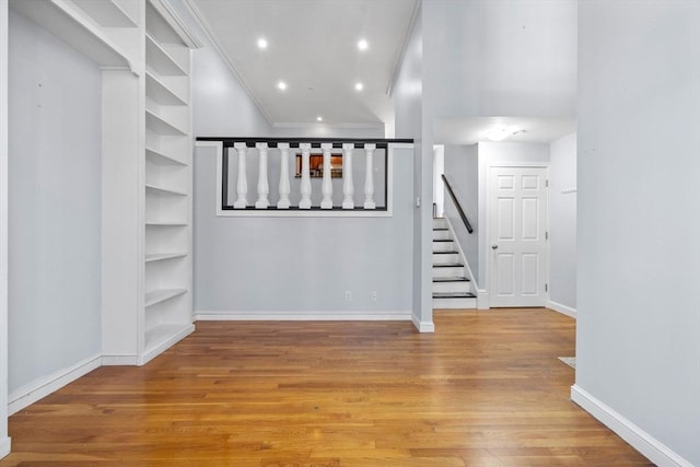 below grade area with stairs, recessed lighting, baseboards, wood finished floors, and ornamental molding