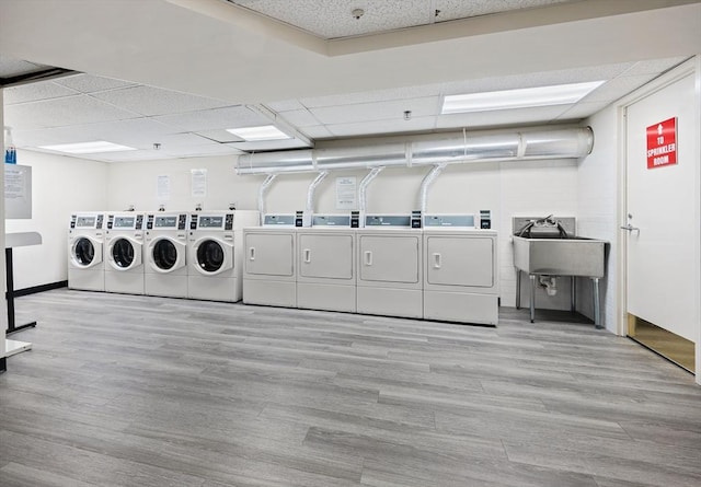 laundry room with sink, washer and clothes dryer, and light hardwood / wood-style flooring