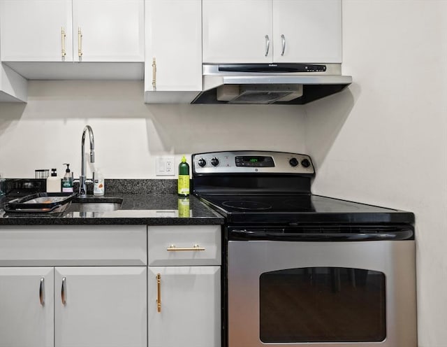 kitchen featuring dark stone countertops, sink, stainless steel electric stove, and white cabinetry