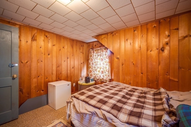 carpeted bedroom with white refrigerator and wooden walls