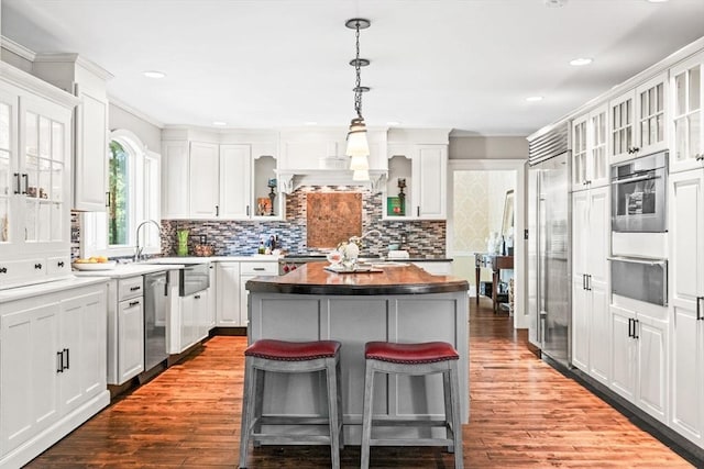 9 Wescott Rd, Andover, MA 01810 - kitchen featuring a warming drawer, a kitchen bar, a kitchen island, a sink, and white cabinetry