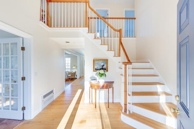 staircase with wood-type flooring and a high ceiling