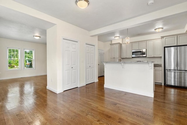 111-113 Pleasant St, Milton, MA 02186 - kitchen featuring stainless steel appliances, dark wood-style flooring, a breakfast bar, a center island with sink, and open floor plan