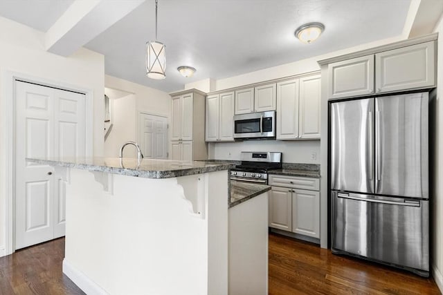 111-113 Pleasant St, Milton, MA 02186 - kitchen with stainless steel appliances, a breakfast bar area, dark wood-style floors, dark stone countertops, and hanging light fixtures