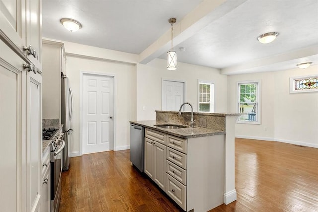 111-113 Pleasant St, Milton, MA 02186 - kitchen with stainless steel appliances, dark wood-type flooring, an island with sink, stone counters, and decorative light fixtures
