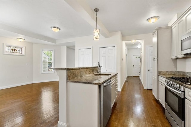 111-113 Pleasant St, Milton, MA 02186 - kitchen with stainless steel appliances, dark wood-type flooring, dark stone counters, a center island with sink, and hanging light fixtures