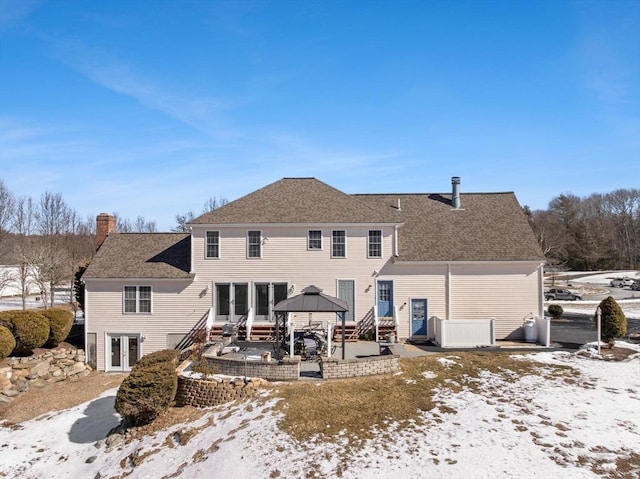 snow covered property with a shingled roof, a chimney, a gazebo, and central AC unit