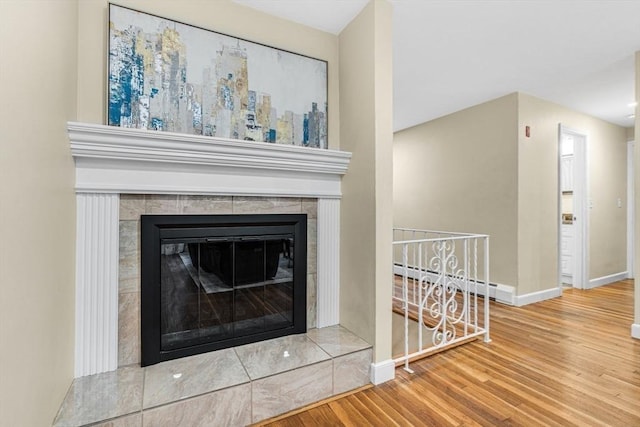 23 Cherokee Rd, Acton, MA 01720 - detailed view of a baseboard radiator, wood finished floors, baseboards, and a tiled fireplace