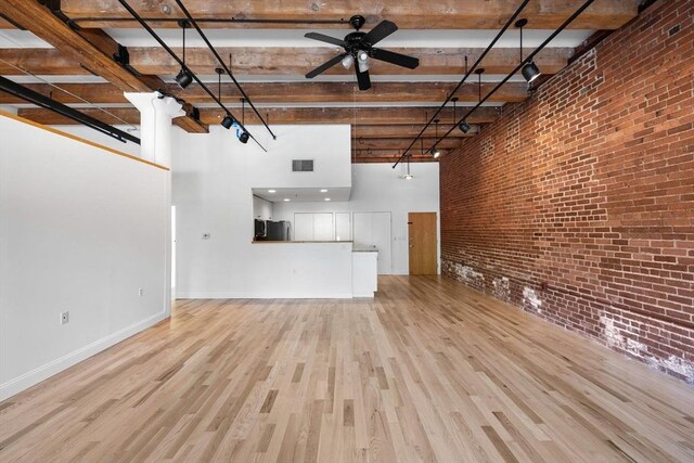 33 Sleeper St Unit 104, Boston, MA 02210 - unfurnished living room with a high ceiling, light wood-style floors, a ceiling fan, brick wall, and baseboards