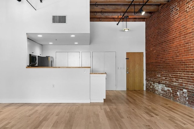 33 Sleeper St Unit 104, Boston, MA 02210 - unfurnished living room with a high ceiling, brick wall, and wood finished floors
