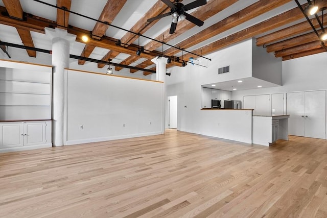33 Sleeper St Unit 104, Boston, MA 02210 - unfurnished living room featuring a ceiling fan, beamed ceiling, light wood-style floors, and a high ceiling