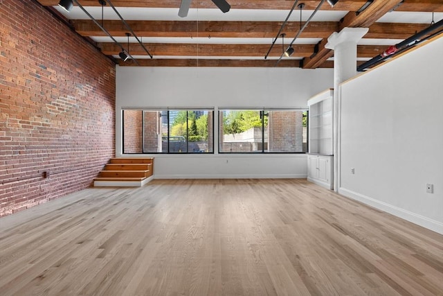 33 Sleeper St Unit 104, Boston, MA 02210 - unfurnished living room with brick wall, beamed ceiling, wood finished floors, ceiling fan, and baseboards