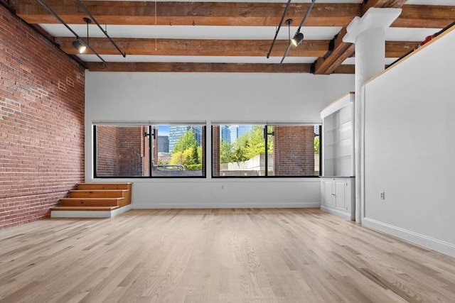 33 Sleeper St Unit 104, Boston, MA 02210 - empty room featuring brick wall, beam ceiling, wood finished floors, and baseboards