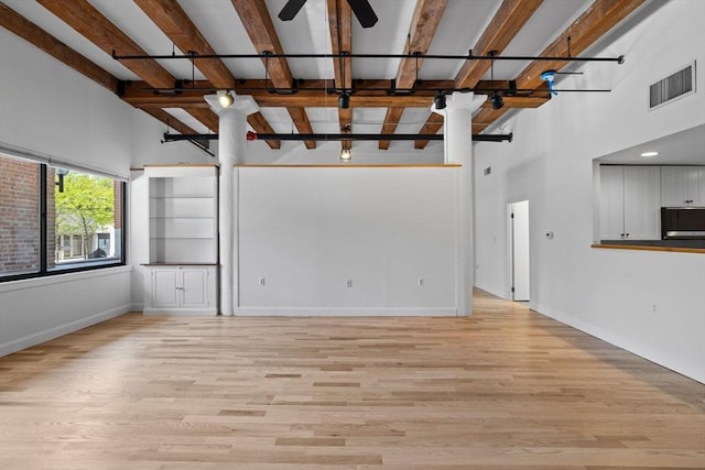 33 Sleeper St Unit 104, Boston, MA 02210 - unfurnished living room with light wood-style floors, a high ceiling, baseboards, a ceiling fan, and beamed ceiling