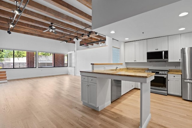 33 Sleeper St Unit 104, Boston, MA 02210 - kitchen featuring stainless steel appliances, light wood-style flooring, open floor plan, wooden counters, and beam ceiling