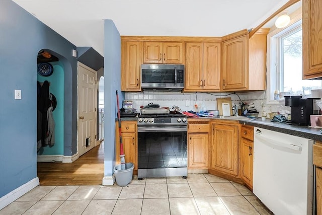 kitchen with appliances with stainless steel finishes, sink, light tile patterned floors, and decorative backsplash