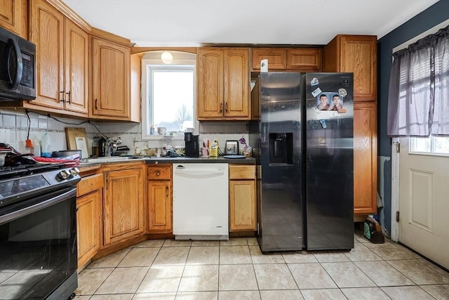 kitchen featuring stainless steel refrigerator with ice dispenser, gas range, tasteful backsplash, light tile patterned floors, and white dishwasher