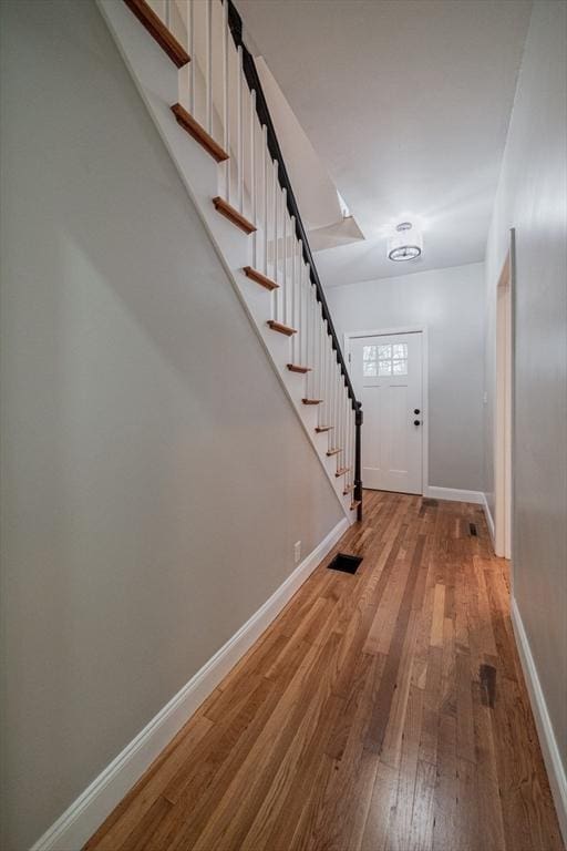 foyer with hardwood / wood-style floors, baseboards, and stairway