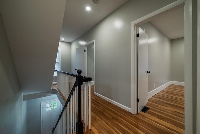 hall featuring an upstairs landing, wood finished floors, baseboards, and recessed lighting