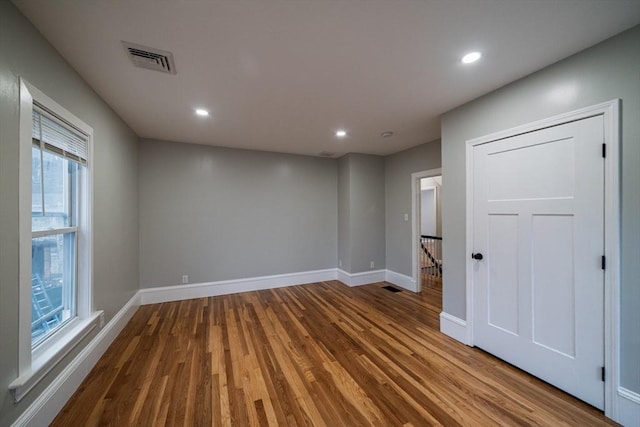 empty room with wood finished floors, baseboards, and recessed lighting