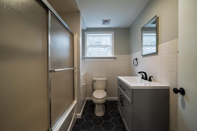 full bath featuring tile patterned flooring, vanity, tile walls, toilet, and a wainscoted wall