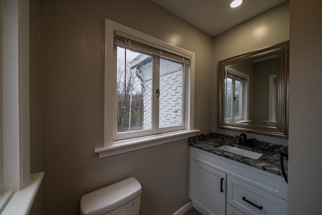 bathroom with plenty of natural light, toilet, vanity, baseboards, and recessed lighting